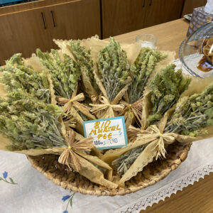A close-up of Mursal tea leaves, showcasing their unique green color and distinctive shape, displayed on a wooden table with a rustic teapot in the background.